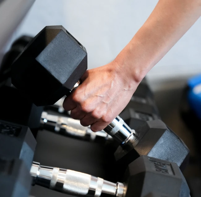 Ręka sięgająca po hantel podczas treningu z trenerem osobistym.